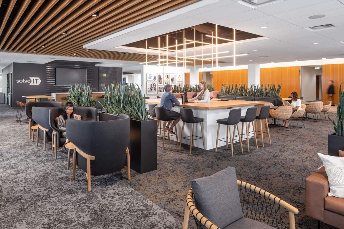 General Mills: Open lounge with high tables, planters, wood-slat ceiling and linear pendant lights