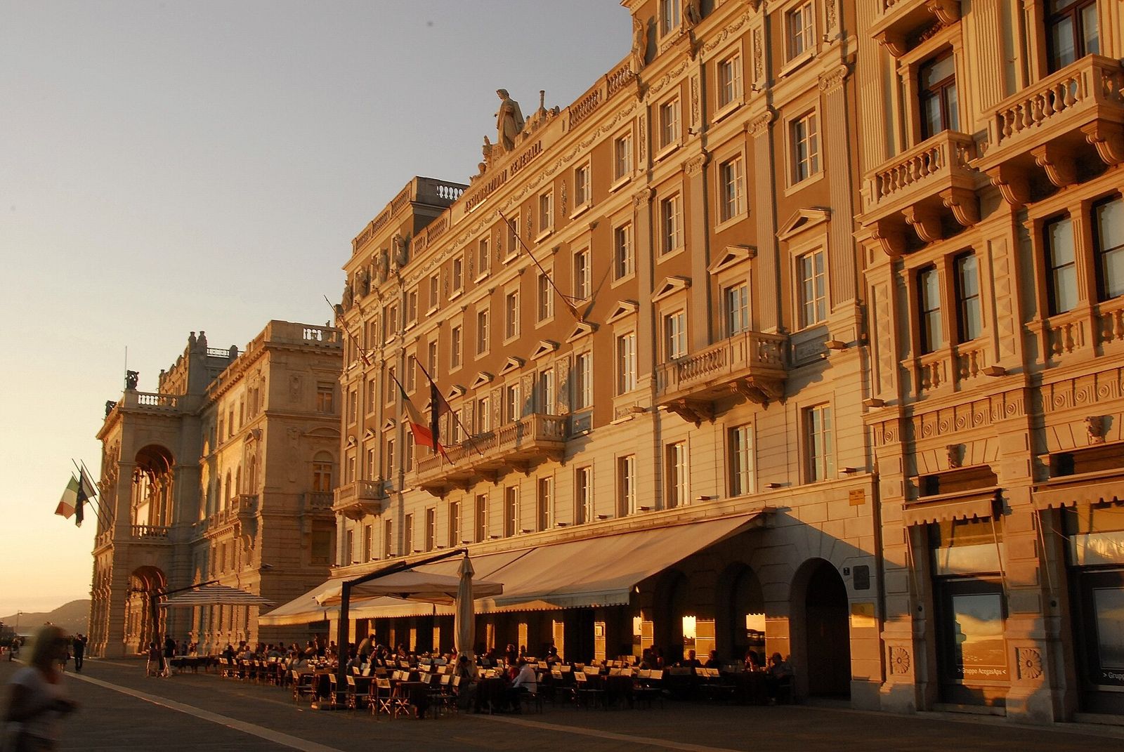 Generali: Palazzo Stratti in evening light with café awnings