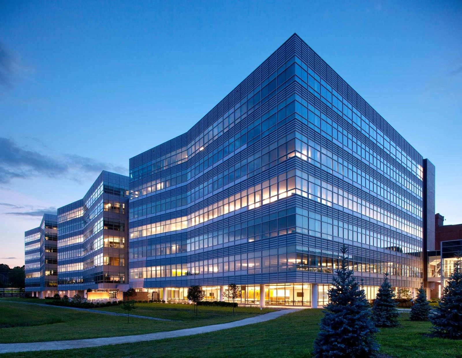 A glass office building with curved edges at dusk