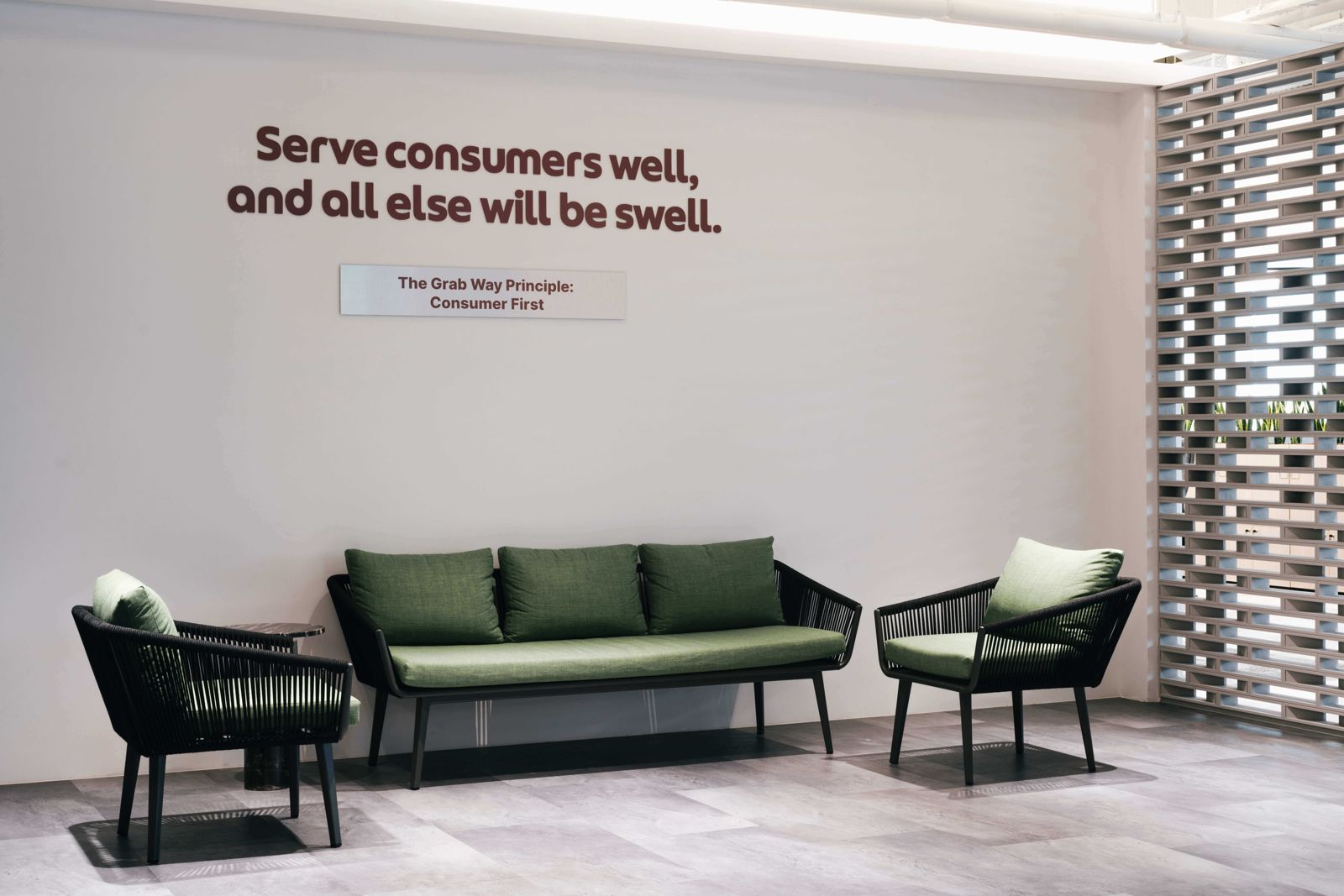 Grab: Green sofa below a wall slogan about serving consumers