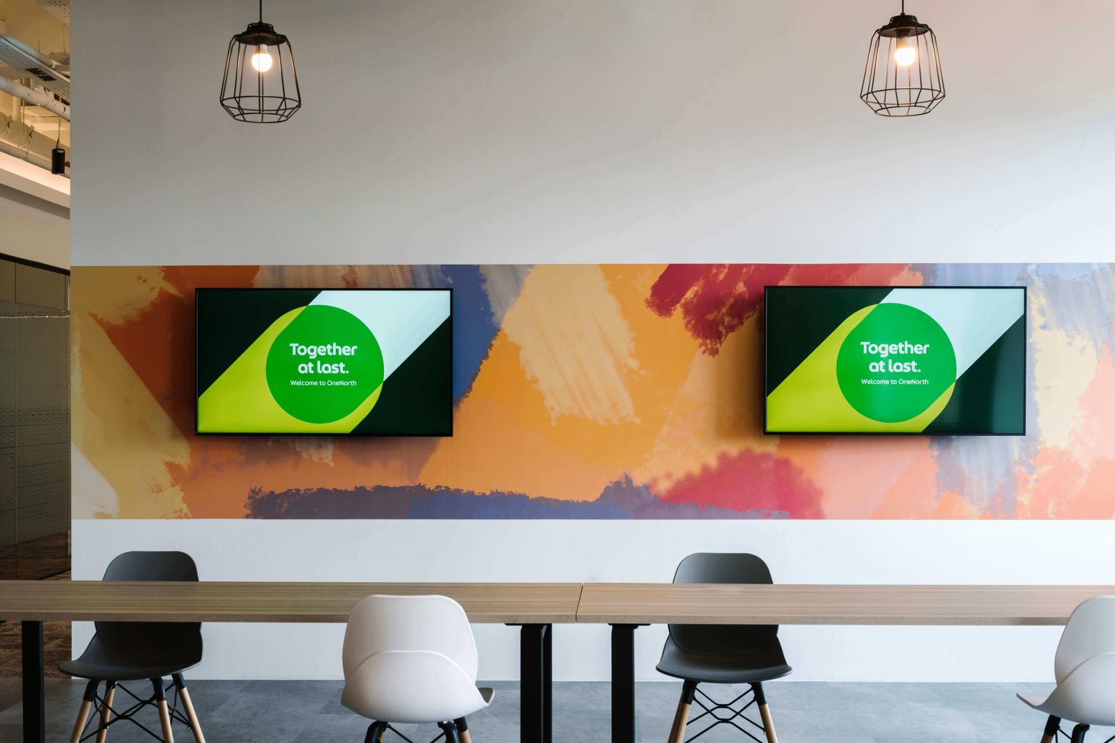 Grab: Long table in front of a painted wall with two screens