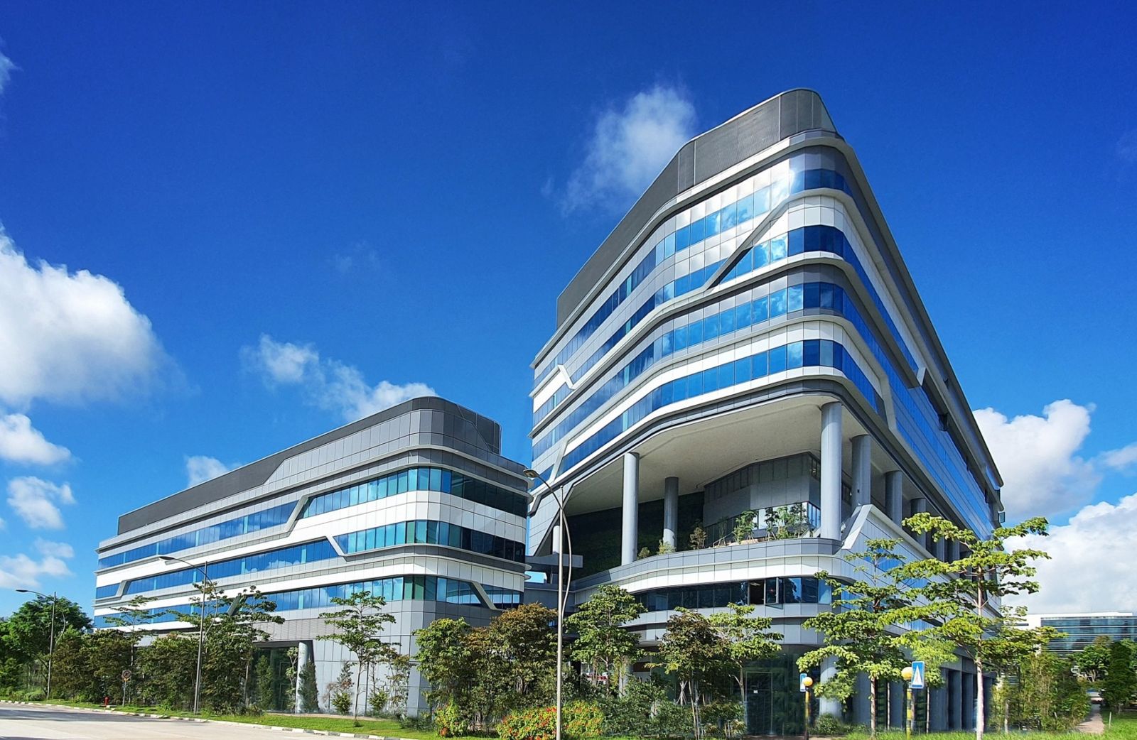 Two curving glass office towers with balconies among trees