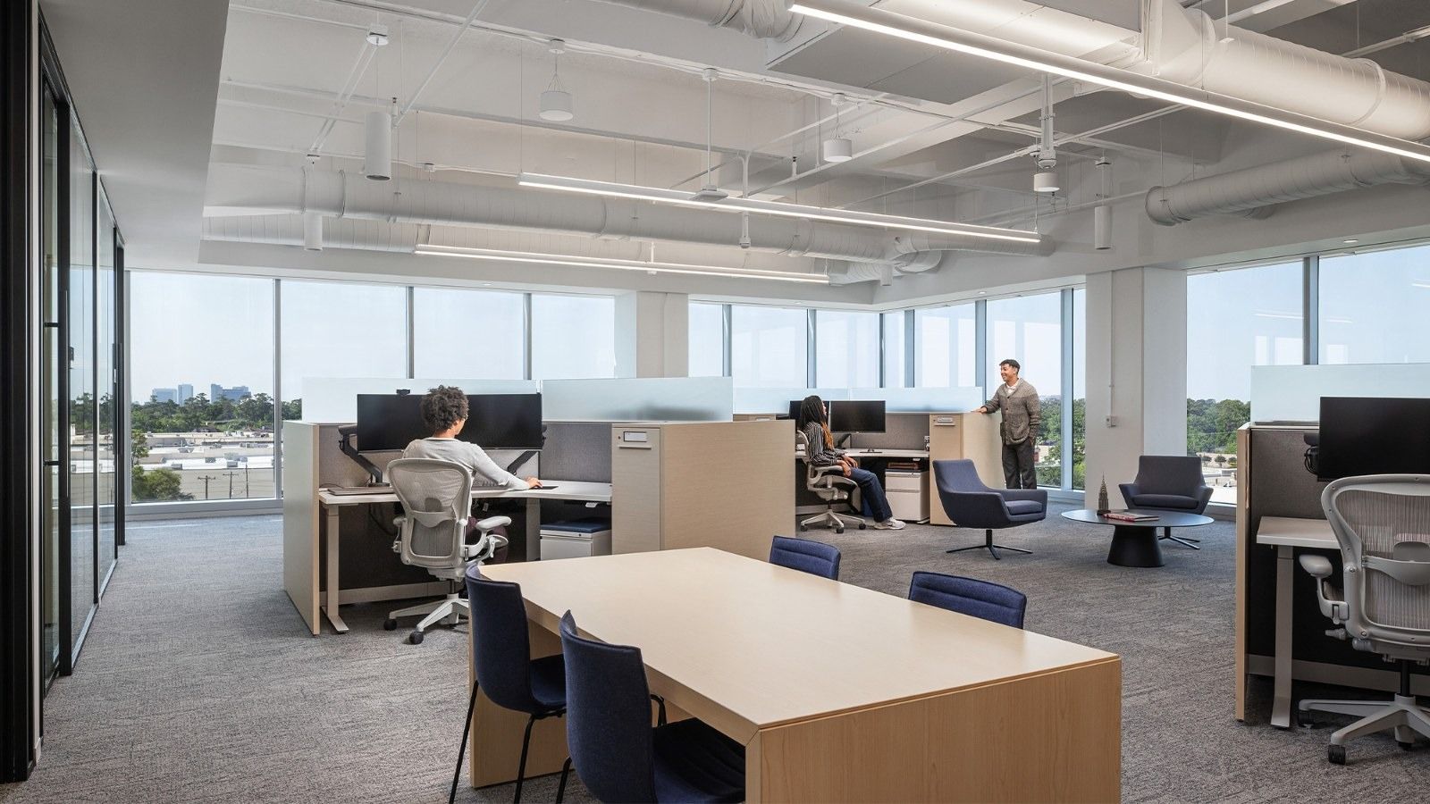 Group 1 Automotive: Open desks and a long table under an open ceiling by windows