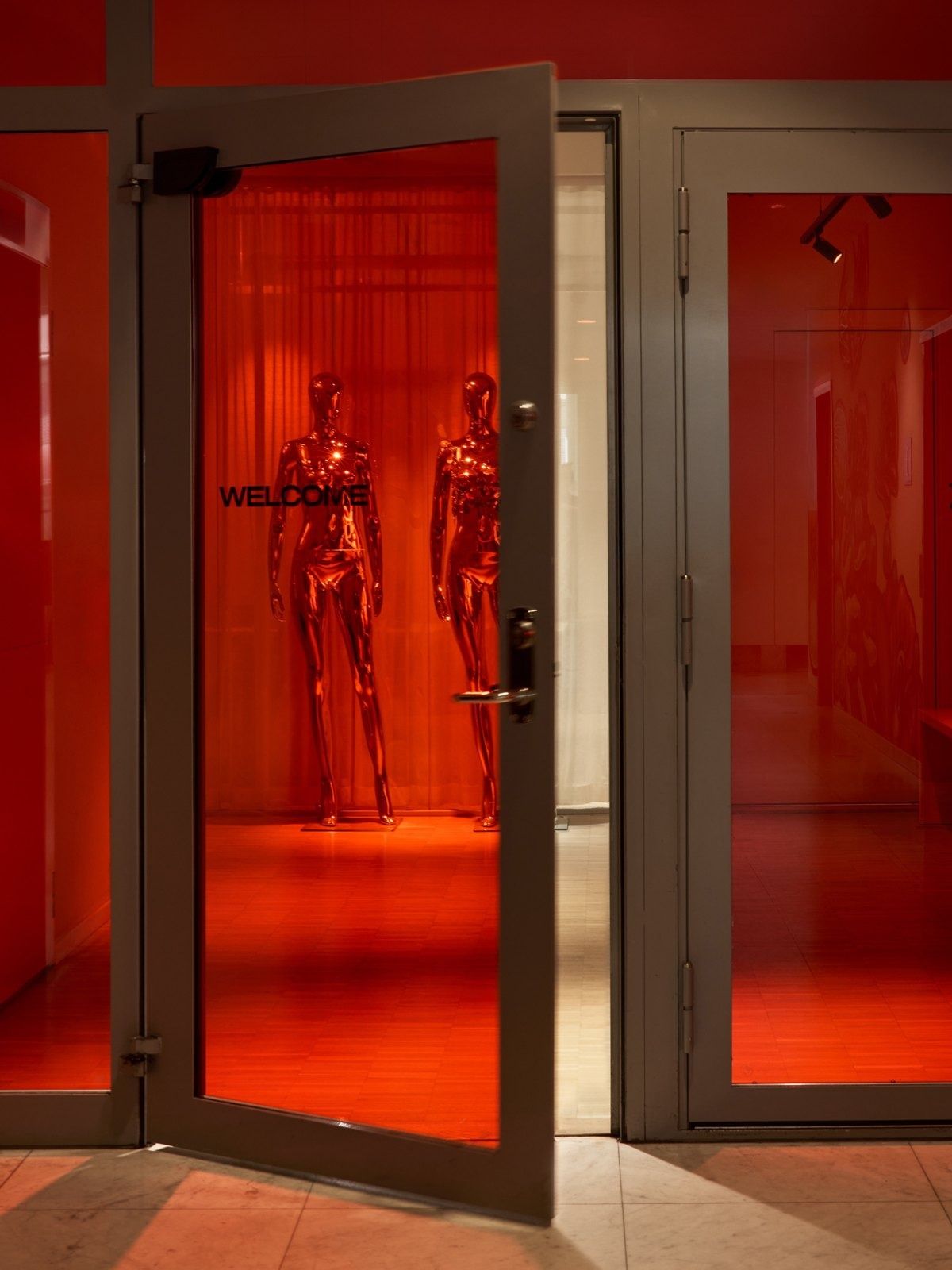 H&M Group: Red-lit glass doors with display mannequins