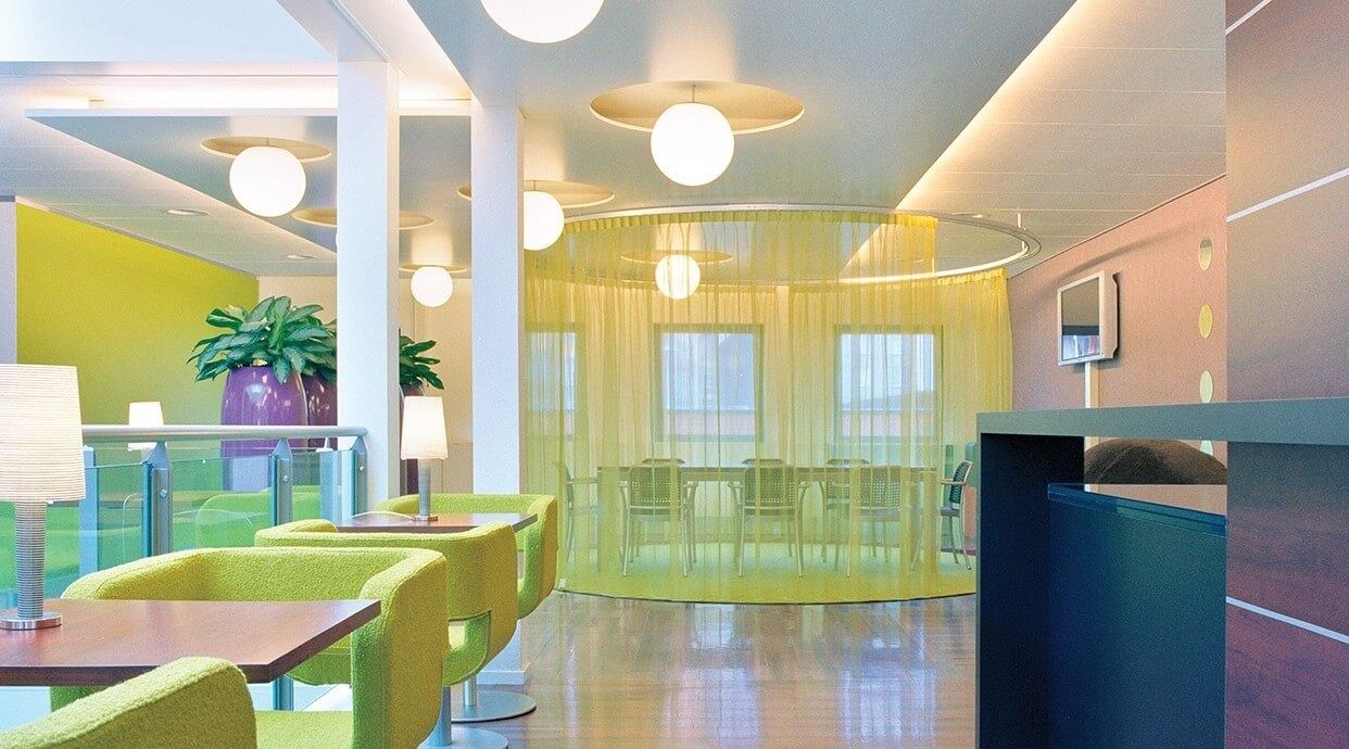 Heineken: Bright lounge with lime-green armchairs, round pendant lamps and a curtained meeting area