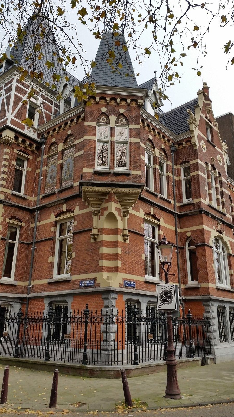 Heineken: Corner of a red-and-cream brick villa with a slate turret and iron railings