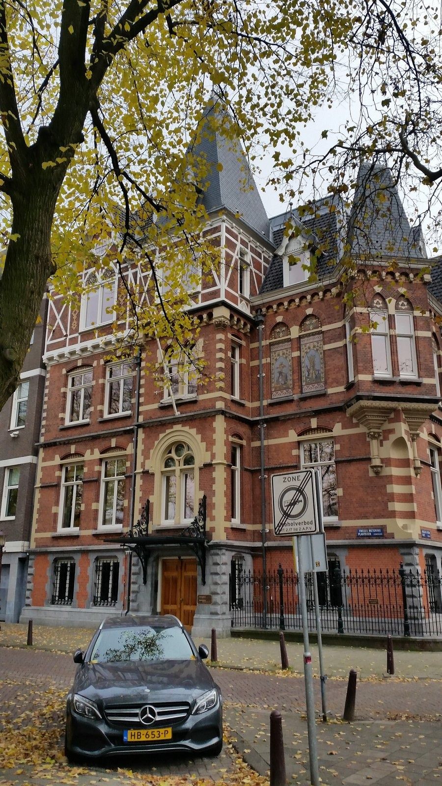 Heineken: Front facade of a red-brick villa with a pointed slate tower behind autumn trees