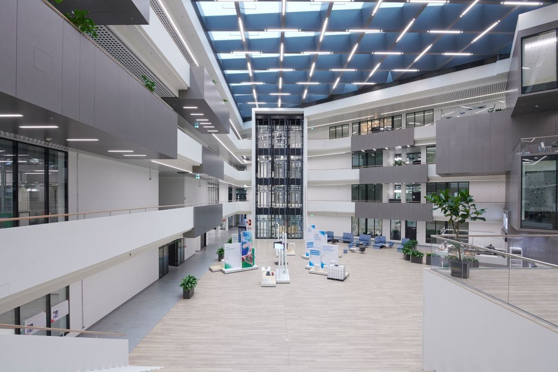 Henkel: Atrium floor with exhibition stands beneath a glass roof and stacked balconies