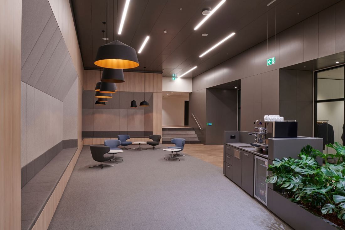 Henkel: Coffee bar with dark wood walls, pendant lamps, armchairs and planters