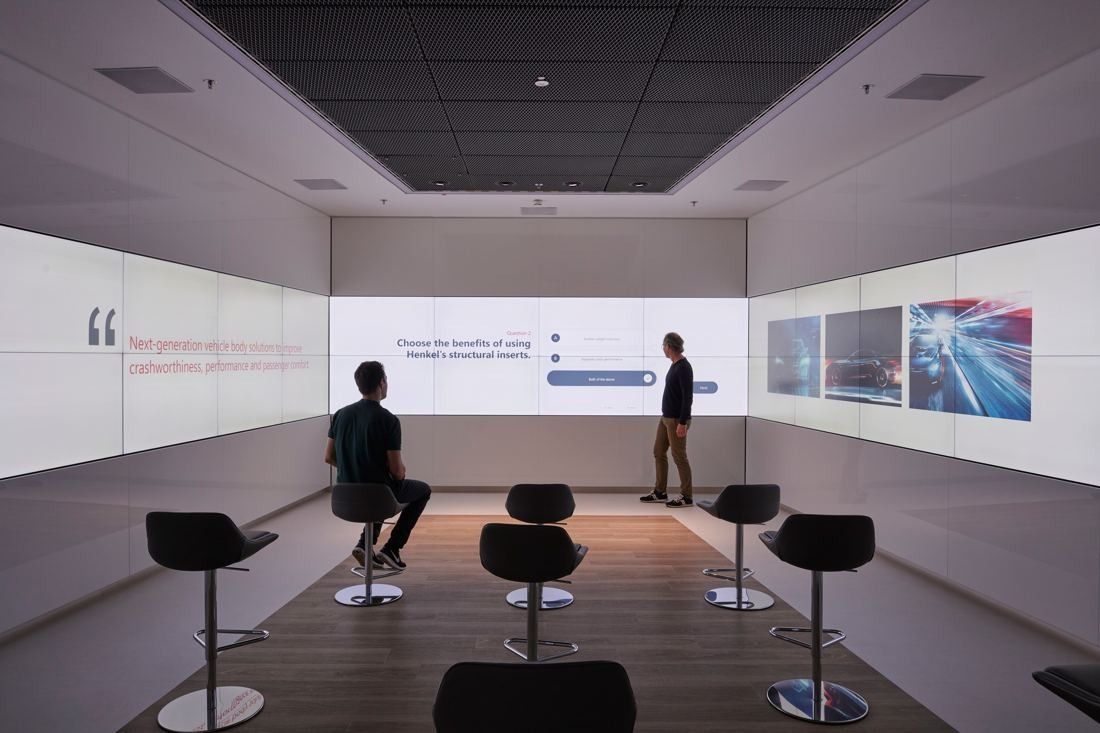 Henkel: Dark presentation room with bar stools facing a large video wall
