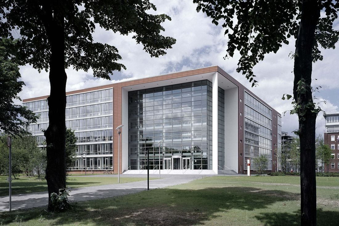 Henkel: Glass and brick office building behind a lawn framed by tall trees