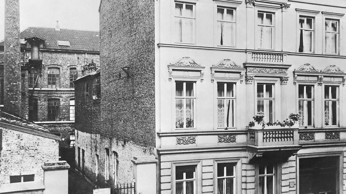 Old photograph of a rear courtyard with a plain building behind a townhouse