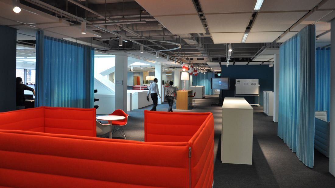 Henkel: Open office with red sofa booths and blue curtains
