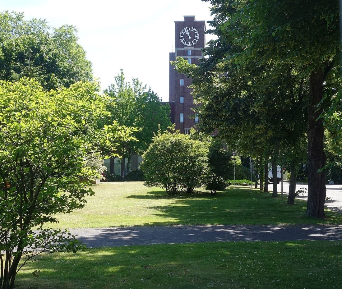 Henkel: Park lawn and trees with a brick clock tower behind