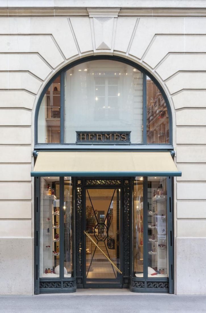 Hermès: Arched shop entrance in a stone façade, with an awning over glass doors