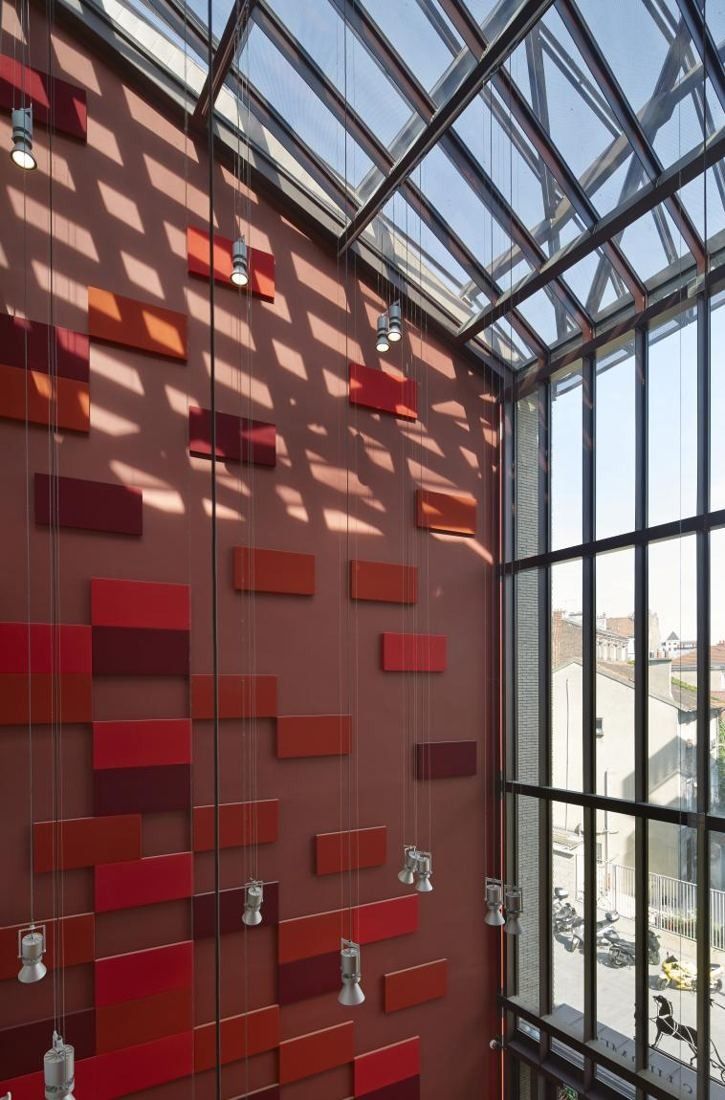 Hermès: Atrium with a red wall of raised panels under a glass roof
