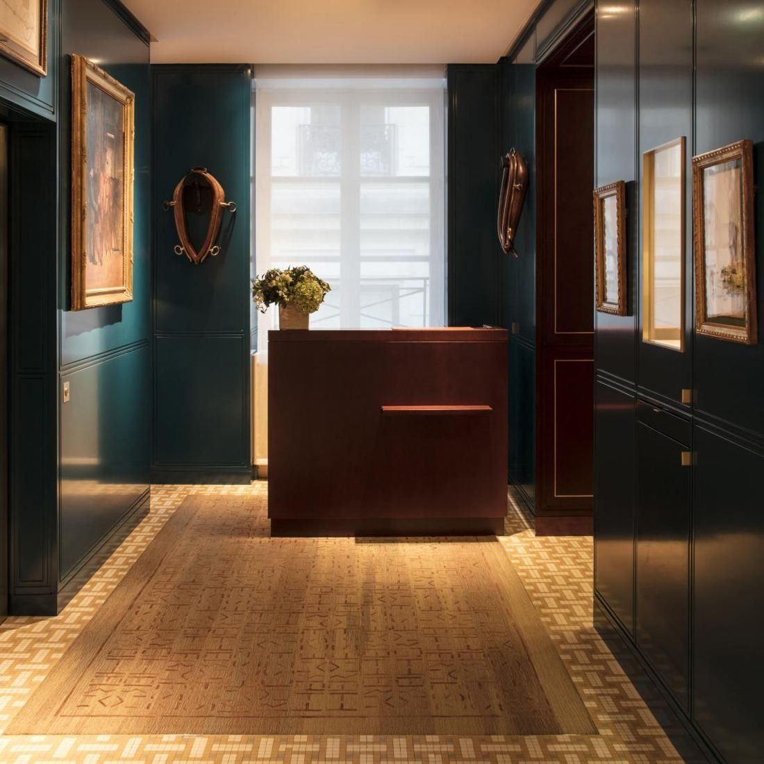 Hermès: Dark green panelled room with a wooden counter and framed pictures