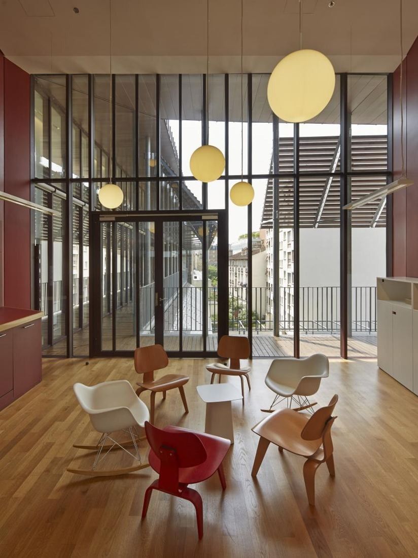 Hermès: Double-height room with globe lights and red and white chairs