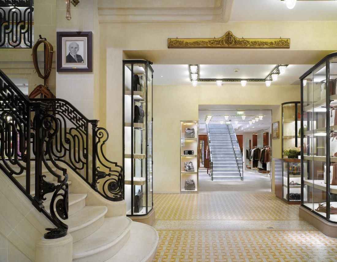 Hermès: Entrance hall with a curved wrought-iron staircase, glass display cases and a mosaic floor