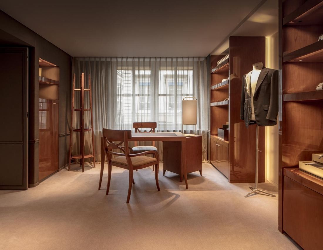 Hermès: Fitting room with wooden shelving, a desk and chair, and sheer curtains
