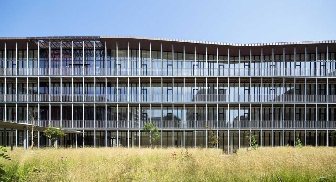 Hermès: Glass-and-metal building with balconies facing a meadow of tall grass