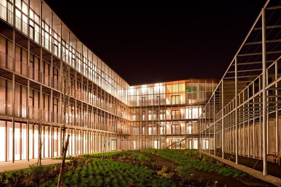 Hermès: Glass buildings lit at night around a planted courtyard
