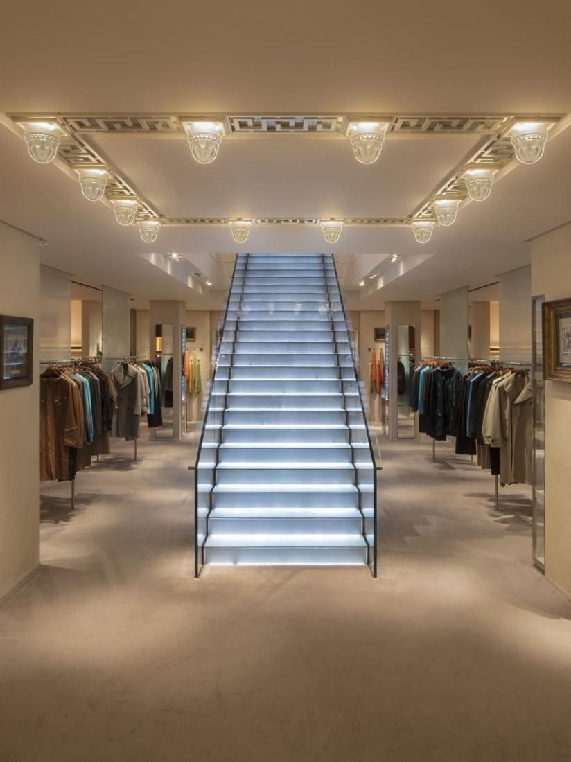 Hermès: Lit glass staircase rising between clothing rails