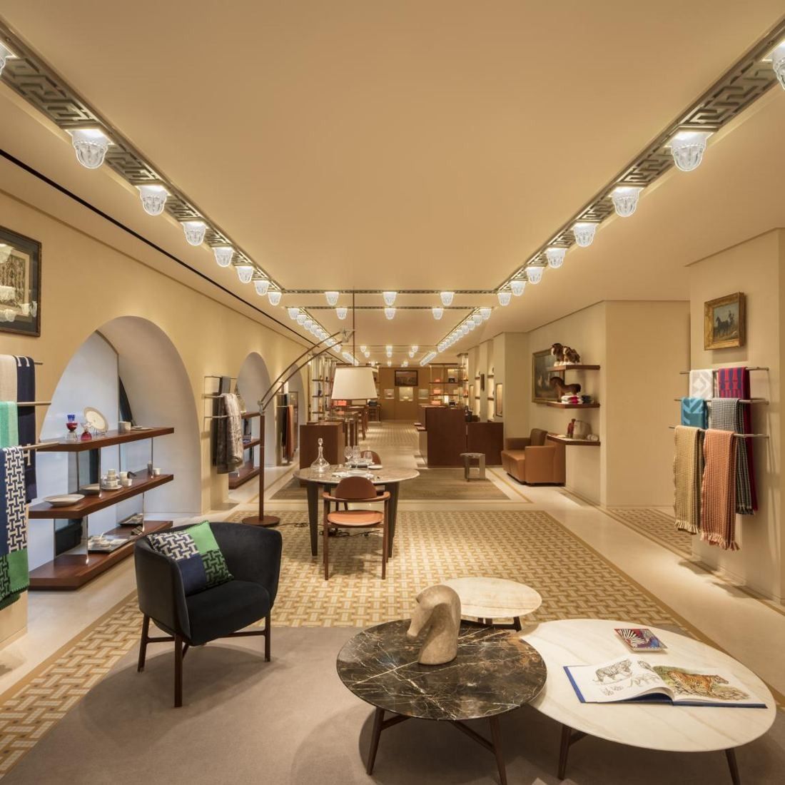 Hermès: Long room with arched windows, low shelves, armchairs and round tables