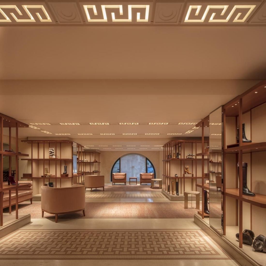 Hermès: Room lined with wooden display shelves, an arched window at the far end