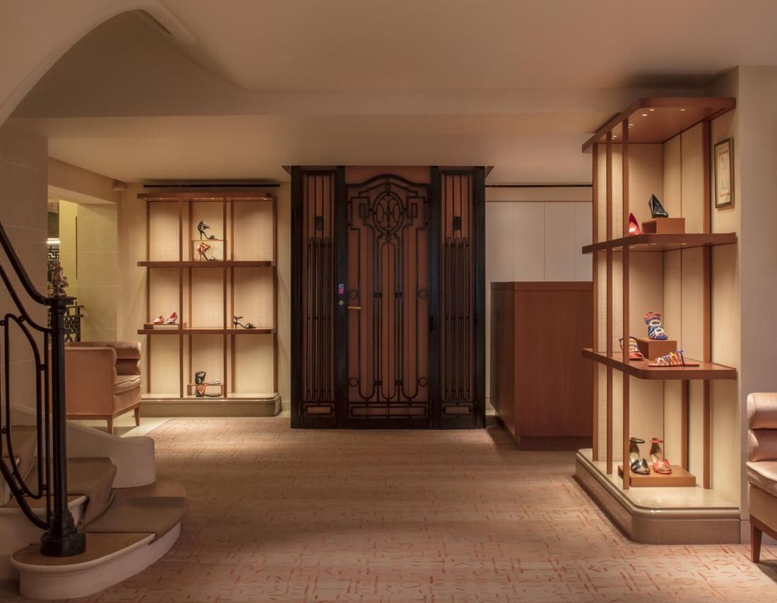 Hermès: Room with open wooden shelving, a carved wooden door and the curve of a staircase