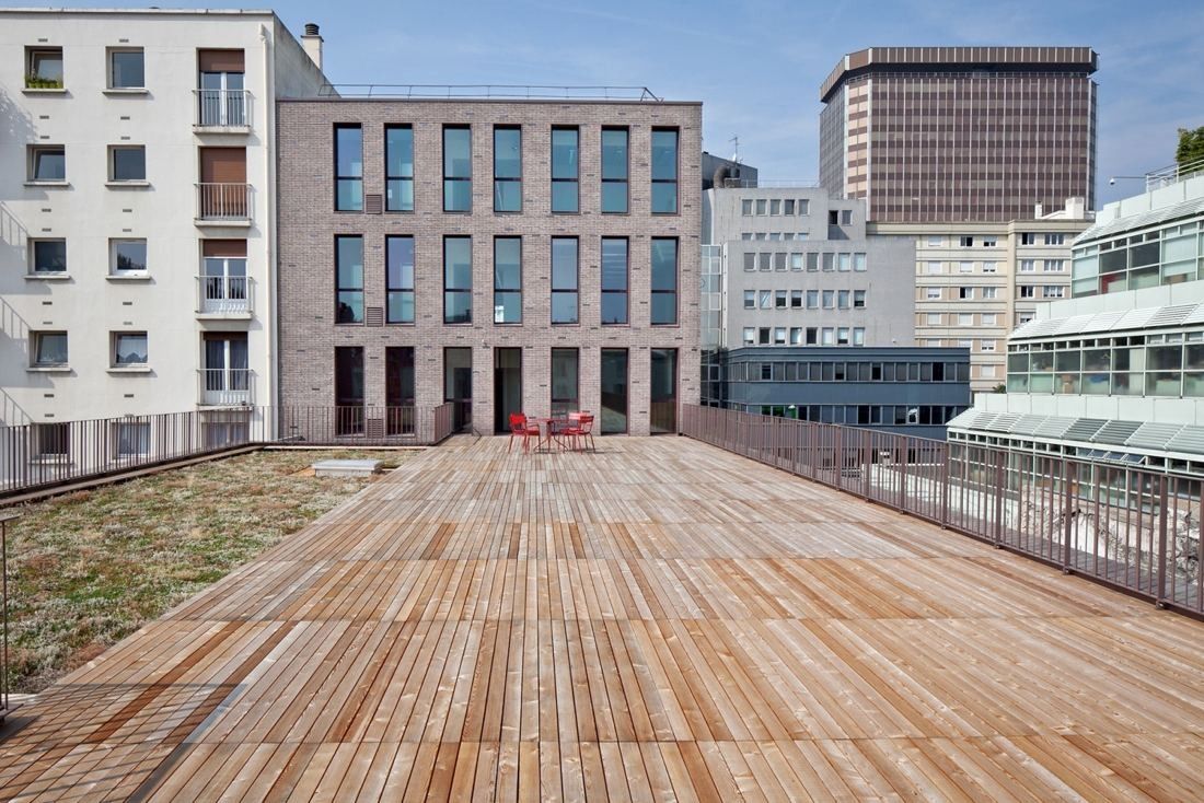 Hermès: Wooden roof terrace with red chairs and surrounding buildings