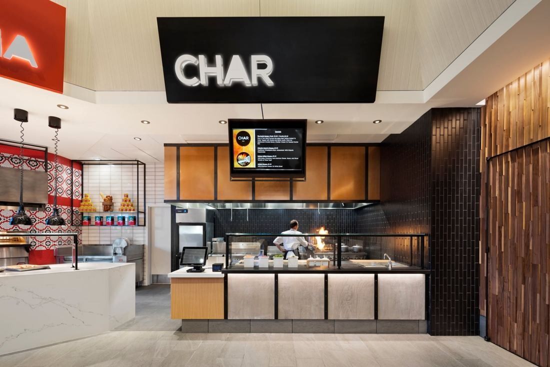 Hilton: Food station with a black CHAR sign, open grill and wood-panelled wall