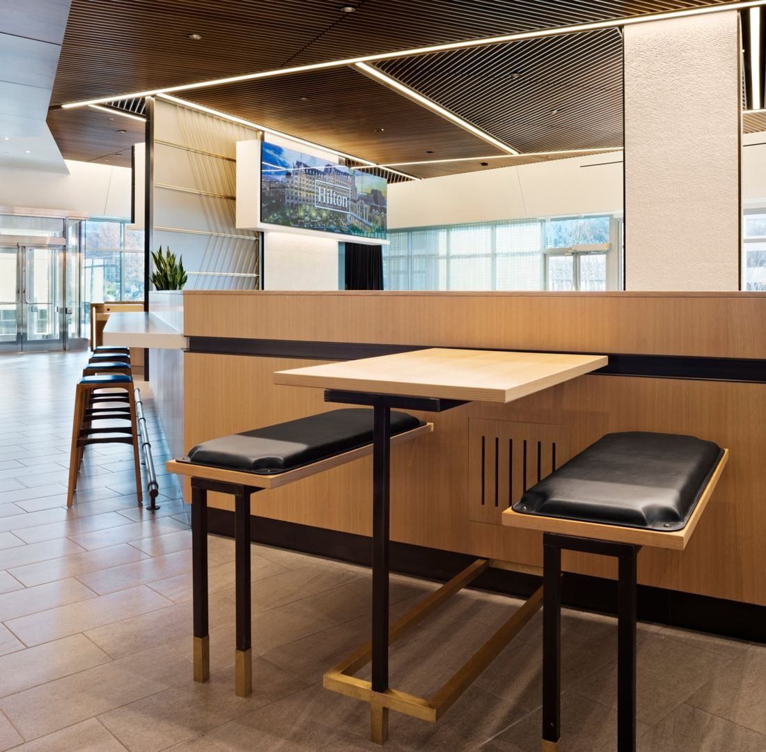 Hilton: High wood tables with stools beside a window wall