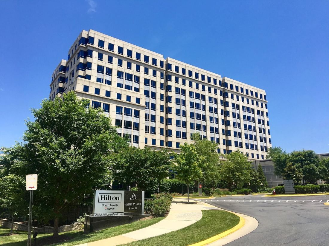 Hilton: Multi-storey office tower with bands of windows behind trees and a curving driveway