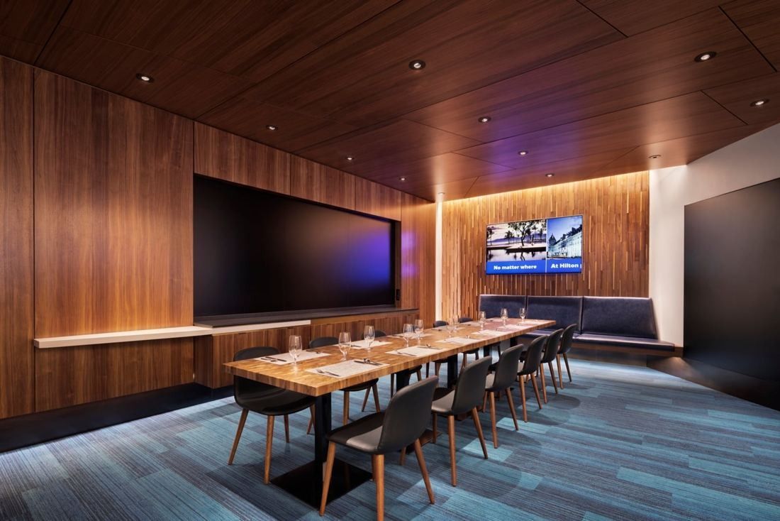 Hilton: Private dining room with walnut-panelled walls, a long table and wall screens