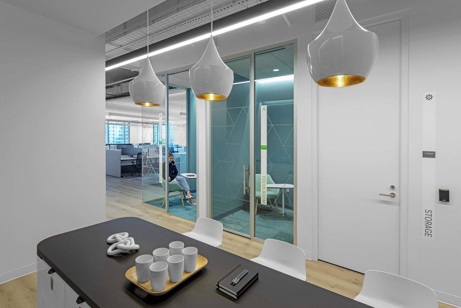 Honeywell: Meeting table under pendant lamps beside glass rooms