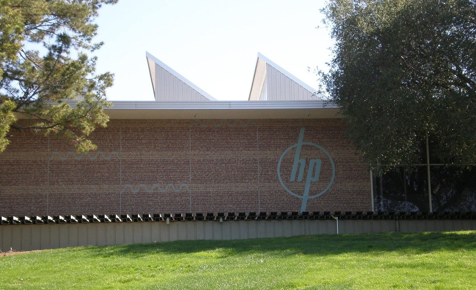HP Inc.: A brick wall with the HP logo under sawtooth roofs