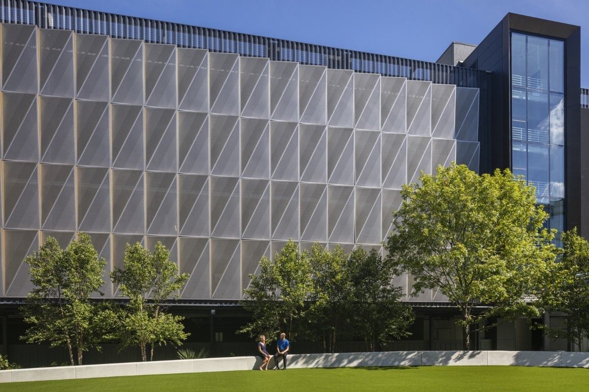Hewlett Packard Enterprise: Building facade of folded triangular metal panels behind trees and a lawn