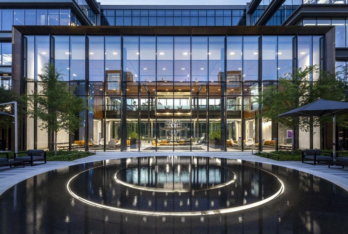 Hewlett Packard Enterprise: Circular reflecting pool with ring lighting in front of a glass entrance hall at night