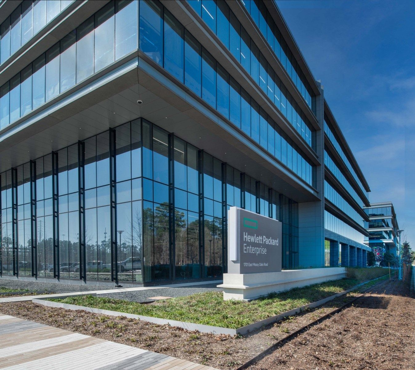 Hewlett Packard Enterprise: Corner of a glass office building with a monument sign and landscaping