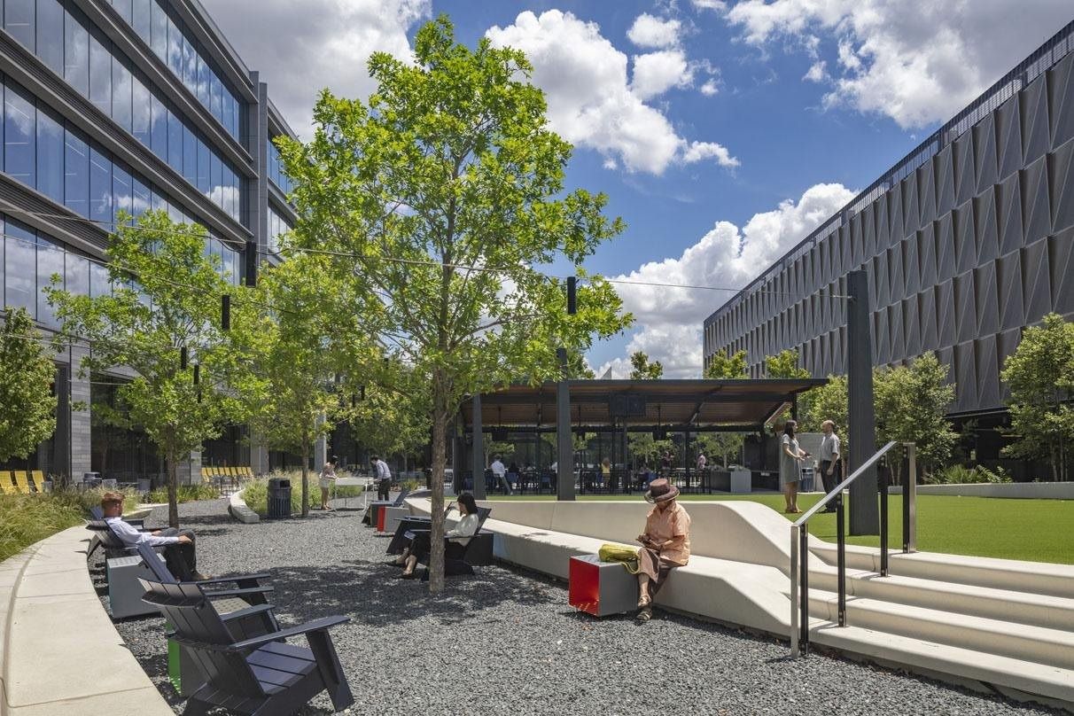 Hewlett Packard Enterprise: Courtyard with trees, gravel, Adirondack chairs, a covered pavilion and a lawn between two buildings