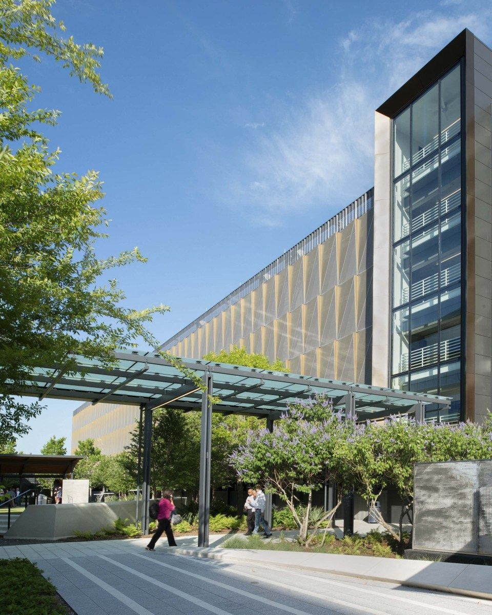 Hewlett Packard Enterprise: Covered walkway leading to a tall glass building with trees along the path