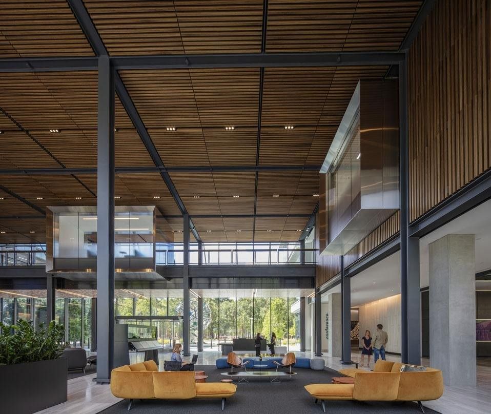 Hewlett Packard Enterprise: Double-height lobby with a wood-slat ceiling, steel columns and orange lounge sofas