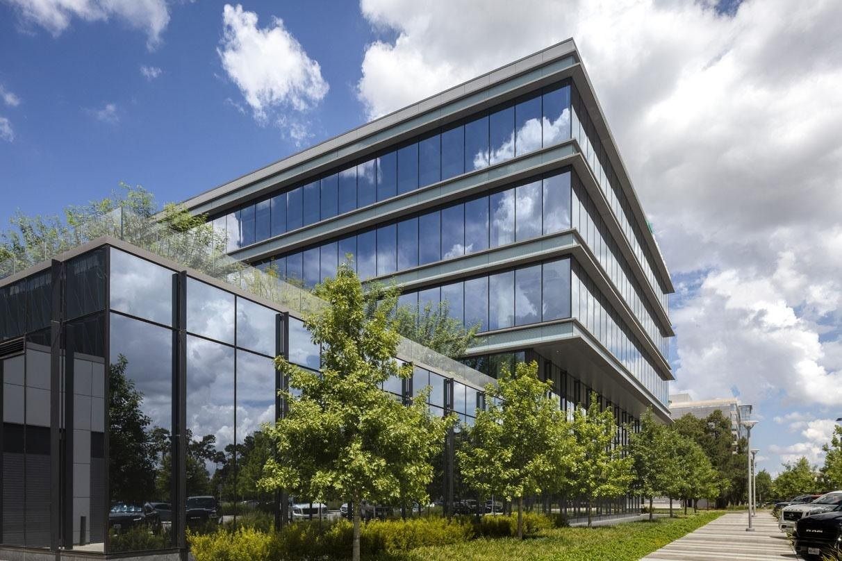 Hewlett Packard Enterprise: Glass office building with stacked horizontal bands and planted roof terraces under a cloudy sky