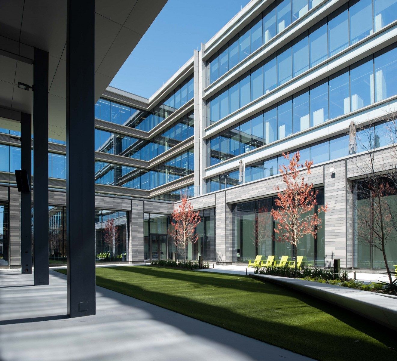 Hewlett Packard Enterprise: Glass office wings seen from beneath a covered colonnade beside a lawn