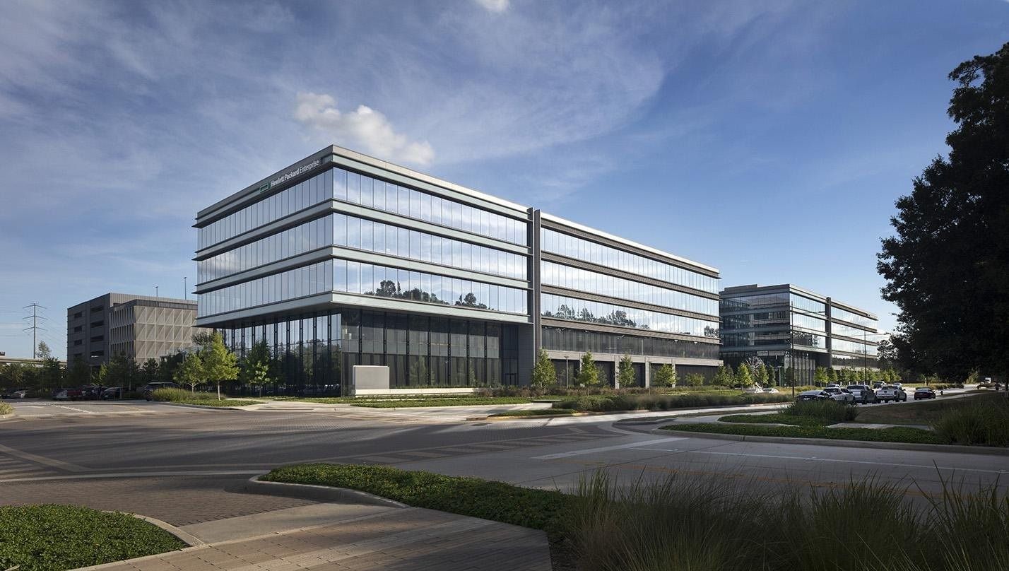 Hewlett Packard Enterprise: Long low glass office building seen across a road and landscaped verge