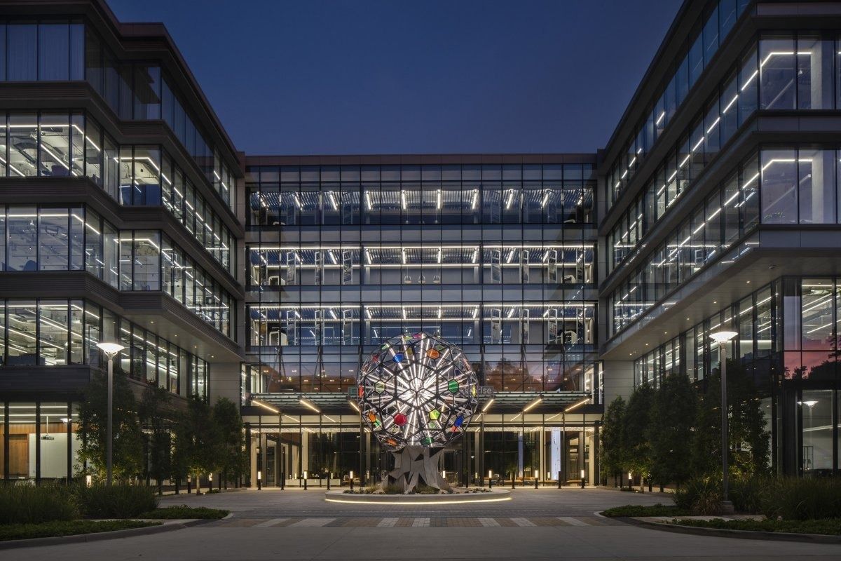Hewlett Packard Enterprise: Spherical metal sculpture in a plaza between lit office wings at night