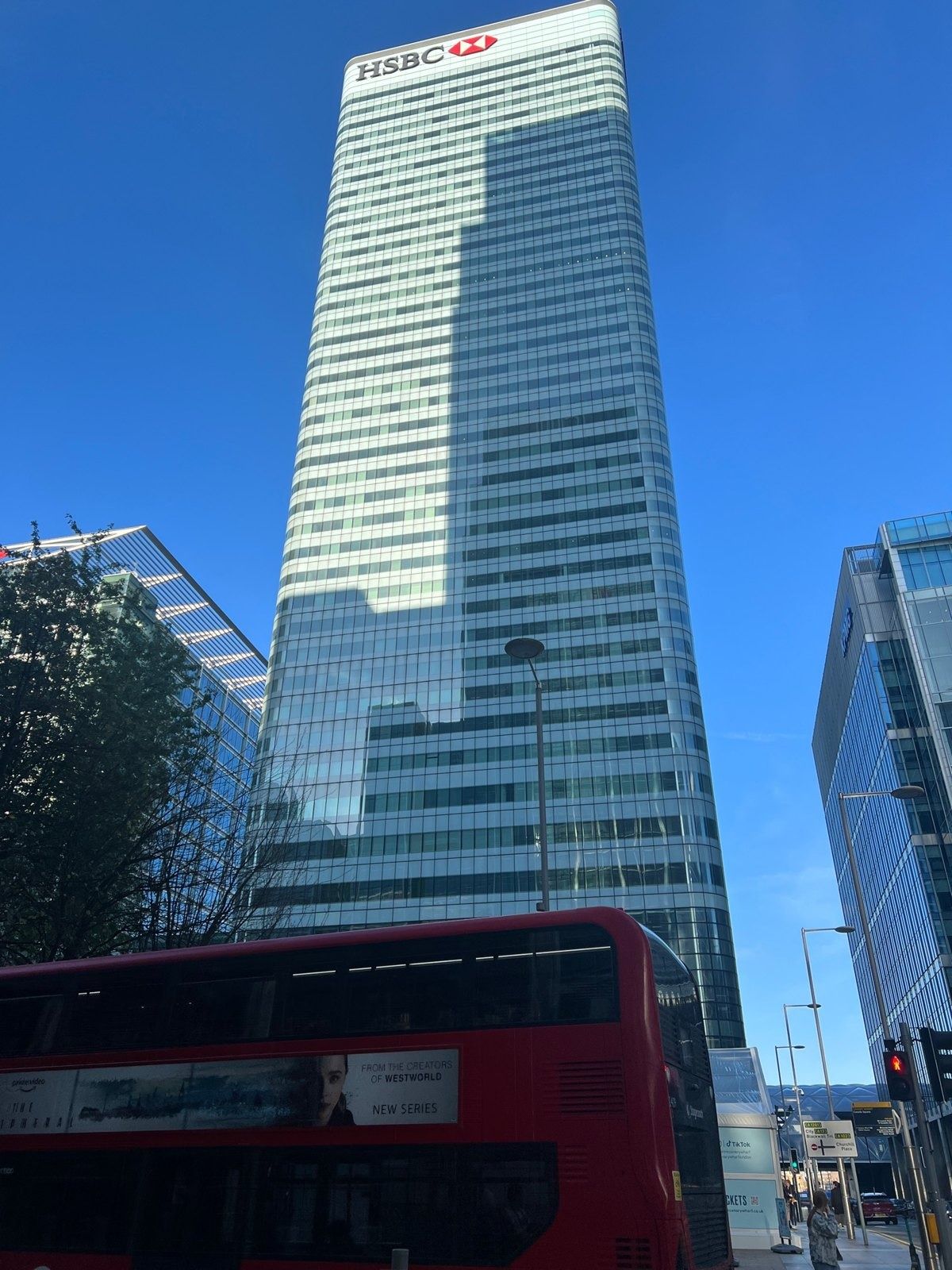 HSBC: Glass tower behind a red double-decker bus and trees
