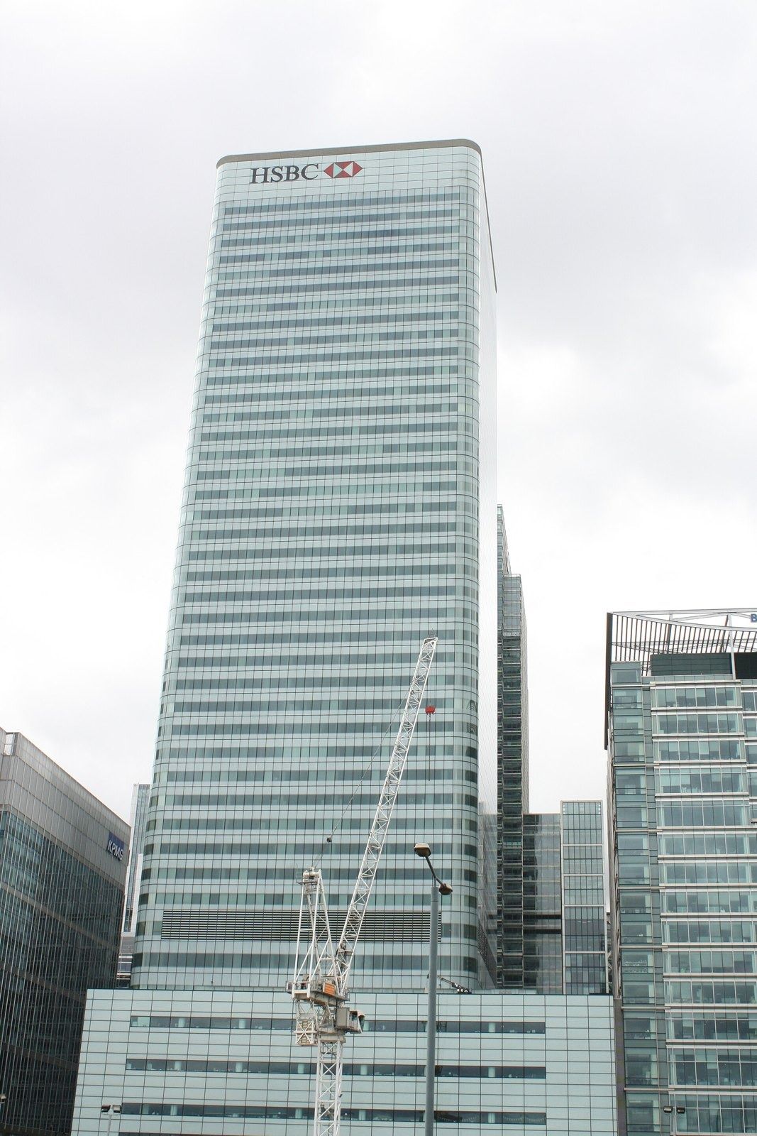 HSBC: Tall glass tower beside other office buildings under a pale sky