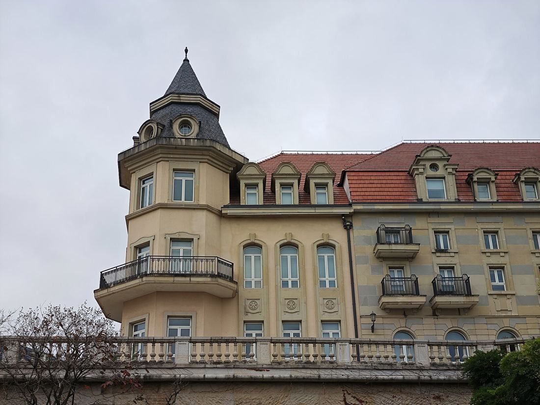 Huawei: Cream building with a corner turret and slate roof, red-tiled roofs behind